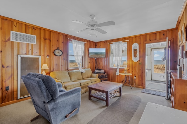 carpeted living room with wooden walls and ceiling fan