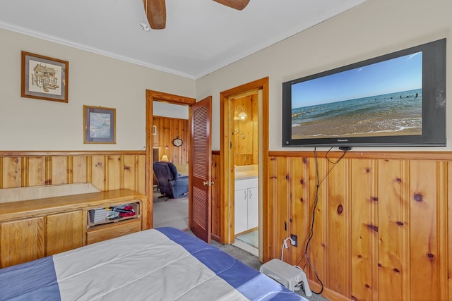 carpeted bedroom featuring connected bathroom, ornamental molding, and wood walls