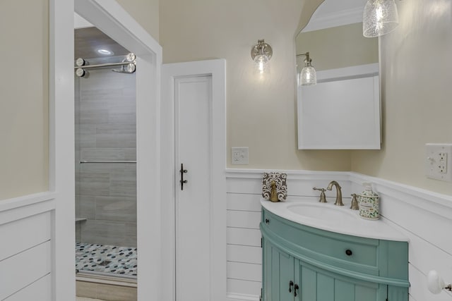 bathroom with tiled shower, vanity, and crown molding