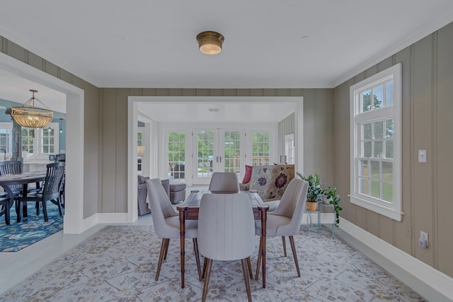 dining area with french doors, ornamental molding, and an inviting chandelier