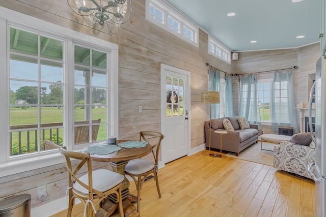 interior space with wooden walls, light hardwood / wood-style flooring, lofted ceiling, and a notable chandelier