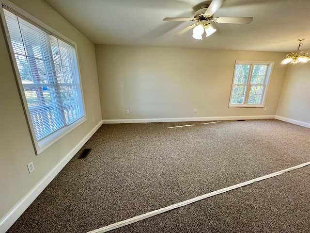 carpeted empty room with ceiling fan with notable chandelier