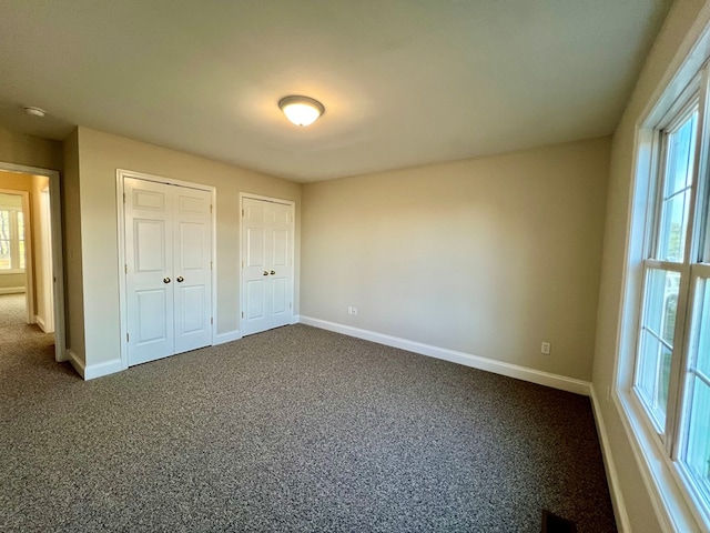 unfurnished bedroom with carpet and multiple closets