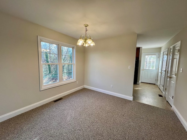 empty room featuring carpet floors and a chandelier