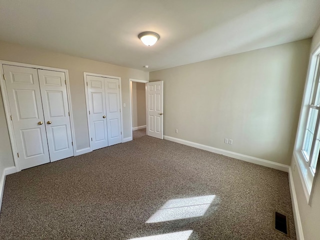 unfurnished bedroom featuring carpet and two closets