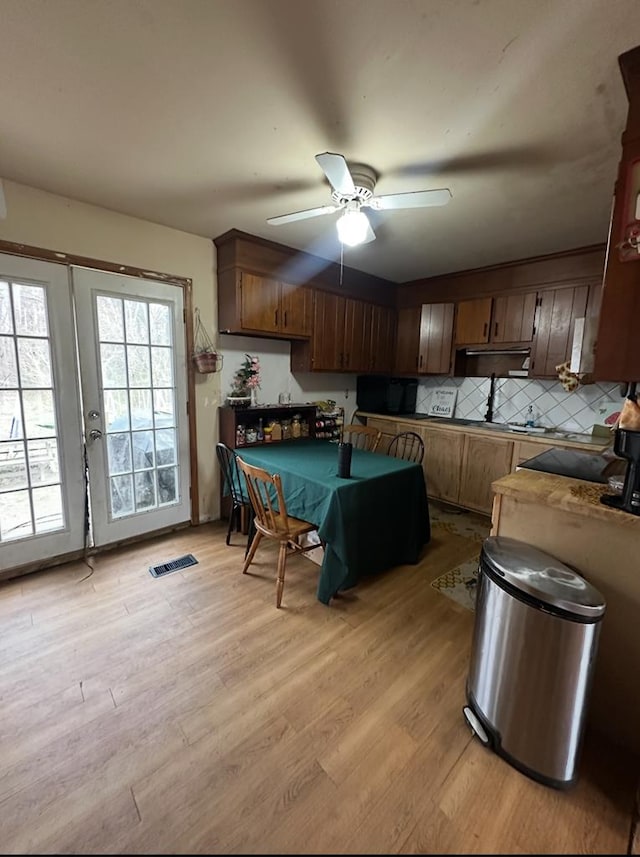 kitchen featuring light wood finished floors, visible vents, tasteful backsplash, and ceiling fan