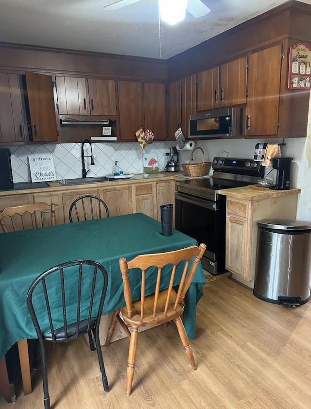 kitchen with tasteful backsplash, stainless steel electric stove, light wood-style floors, a ceiling fan, and a sink