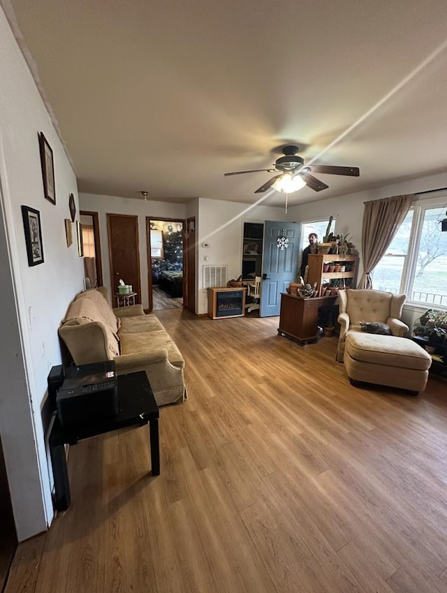 living area featuring visible vents, light wood-type flooring, and ceiling fan