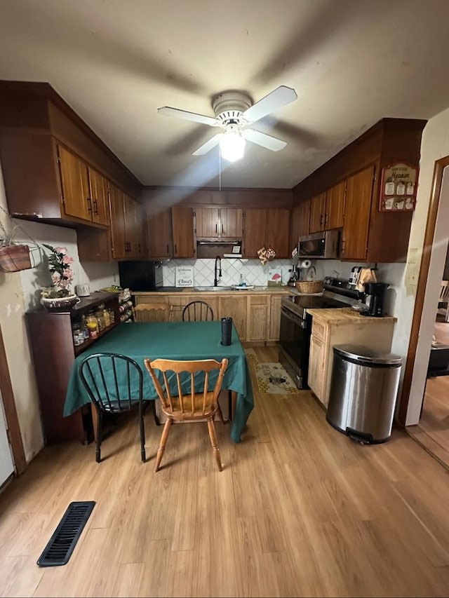 kitchen with stainless steel microwave, electric range, visible vents, and light wood-type flooring