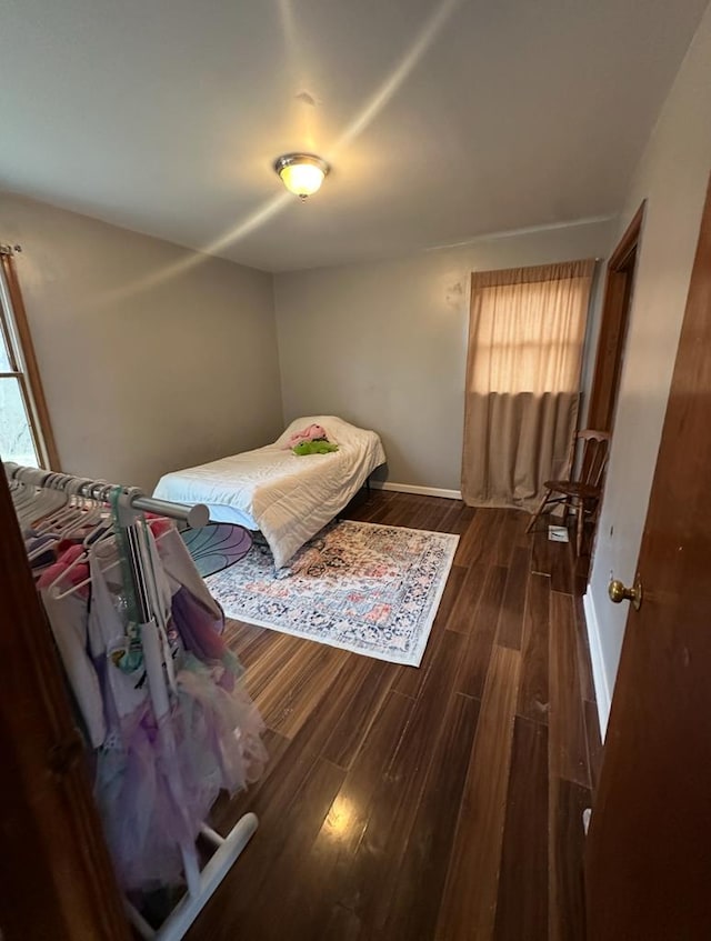 bedroom featuring multiple windows, wood finished floors, and baseboards