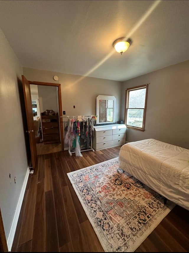 bedroom with baseboards and dark wood-type flooring