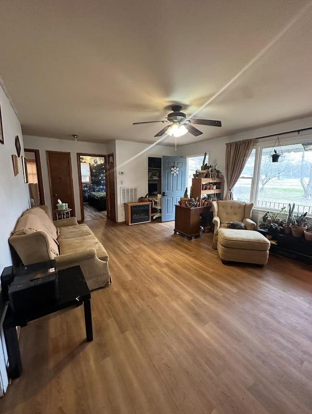 living room featuring visible vents, light wood-type flooring, and ceiling fan