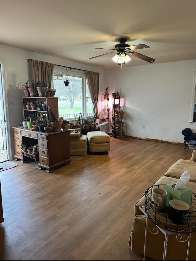 living room featuring wood finished floors, a ceiling fan, and baseboards