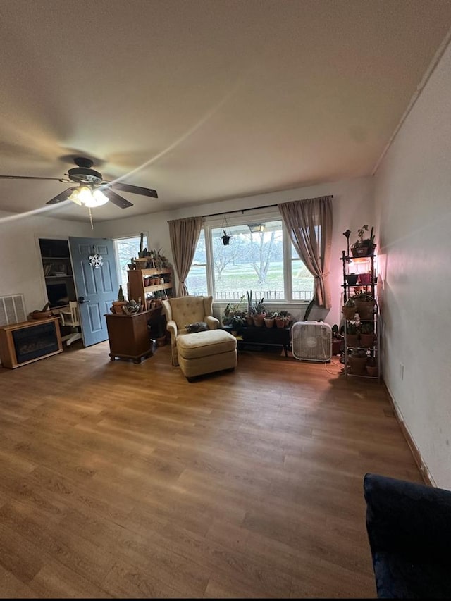 living room featuring visible vents, ceiling fan, and wood finished floors