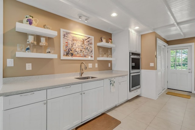 kitchen with light tile patterned flooring, sink, white cabinets, and double oven