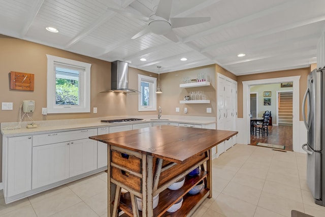 kitchen featuring hanging light fixtures, white cabinetry, appliances with stainless steel finishes, and wall chimney range hood