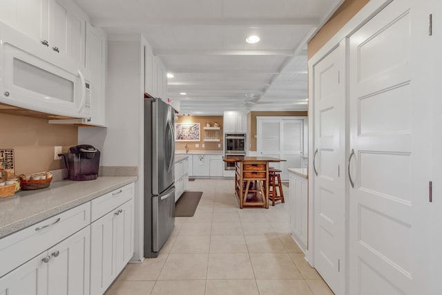 kitchen featuring light tile patterned flooring, appliances with stainless steel finishes, and white cabinets