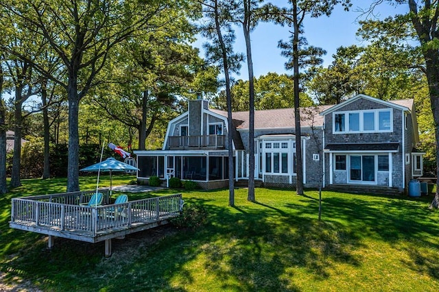 back of property with a yard, a sunroom, and a deck