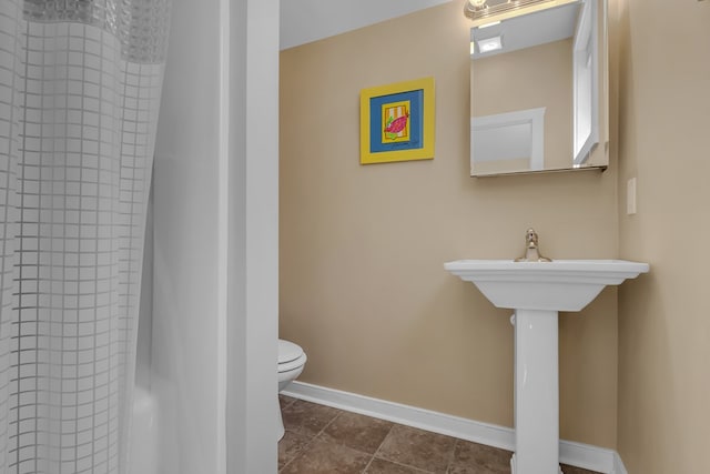 bathroom with tile patterned flooring, walk in shower, and toilet