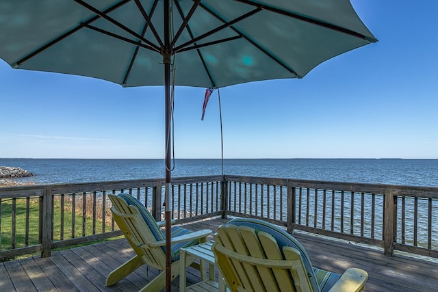 wooden terrace featuring a beach view and a water view