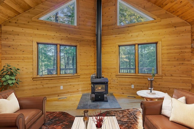 living room featuring high vaulted ceiling, a wood stove, and wooden walls