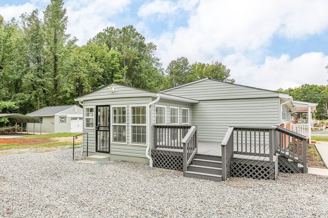 rear view of property with a carport, a wooden deck, and a sunroom