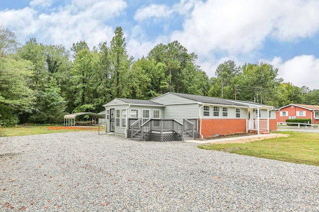 manufactured / mobile home featuring a wooden deck, a carport, and a front yard