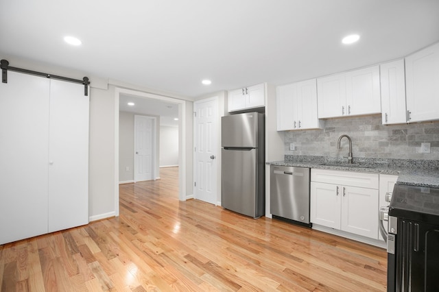 kitchen featuring white cabinetry, sink, a barn door, and appliances with stainless steel finishes