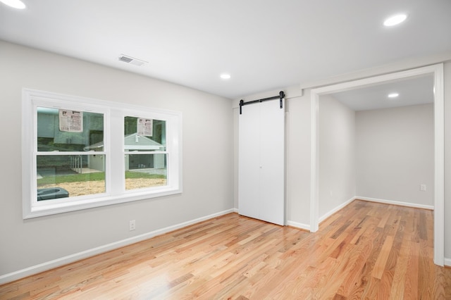 unfurnished room featuring light hardwood / wood-style flooring and a barn door