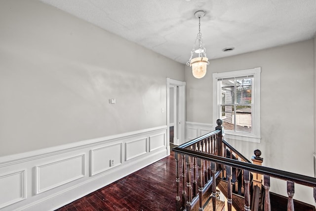 46 Yeocomico Ln, Kinsale, VA 22488 - hall featuring an upstairs landing, wood finished floors, a wainscoted wall, a chandelier, and a textured ceiling