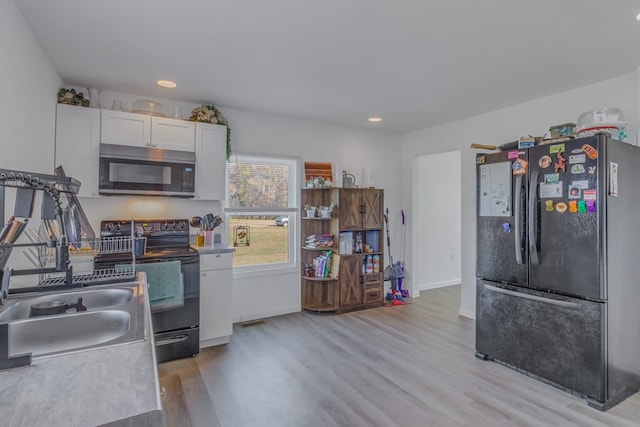 427 Brooks Ln, Callao, VA 22435 - kitchen with sink, light hardwood / wood-style floors, white cabinetry, and black appliances