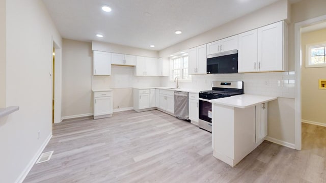 kitchen featuring sink, light hardwood / wood-style flooring, backsplash, white cabinets, and appliances with stainless steel finishes