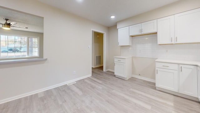 kitchen featuring white cabinets, ceiling fan, light hardwood / wood-style floors, and backsplash