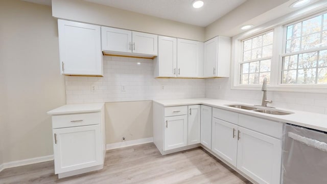 kitchen with white cabinetry, stainless steel dishwasher, light hardwood / wood-style floors, and sink