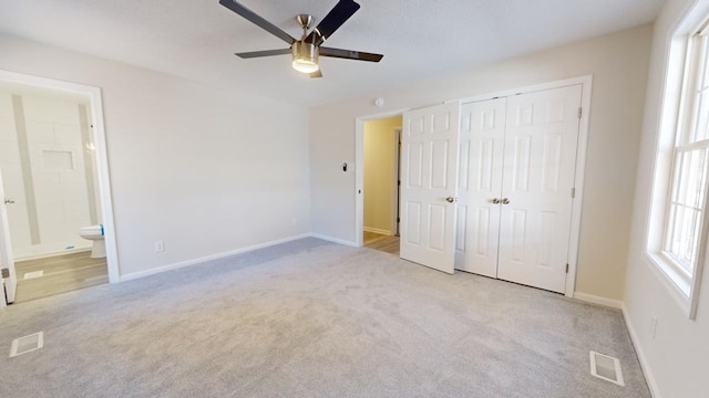 unfurnished bedroom with ceiling fan, a closet, ensuite bathroom, and light colored carpet