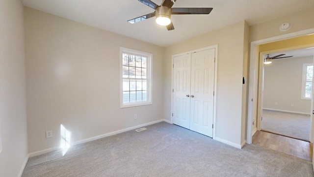 unfurnished bedroom featuring ceiling fan, light colored carpet, and a closet