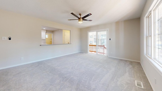 carpeted empty room with ceiling fan and a textured ceiling