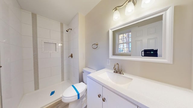 bathroom featuring a tile shower, vanity, toilet, and wood-type flooring