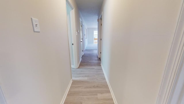 hallway with light wood-type flooring and a textured ceiling