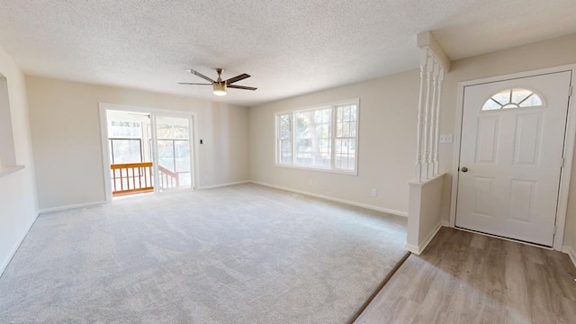 entryway with ceiling fan, light carpet, and a textured ceiling