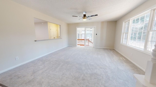 carpeted spare room featuring ceiling fan and a textured ceiling