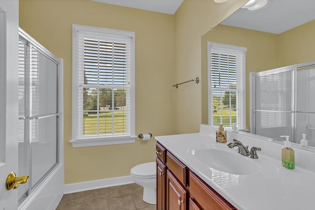 bathroom with tile patterned floors, baseboards, vanity, toilet, and shower / bath combination with glass door
