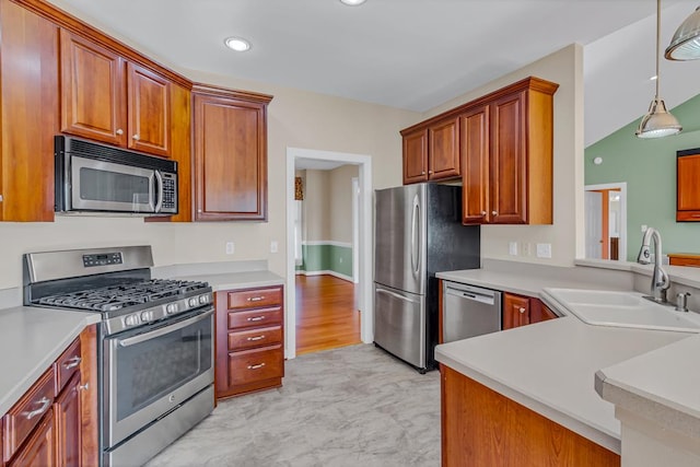 kitchen with brown cabinetry, appliances with stainless steel finishes, hanging light fixtures, a sink, and light countertops