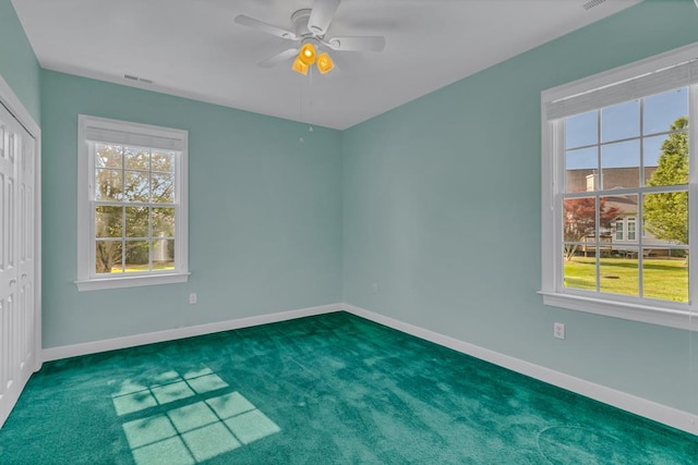carpeted empty room featuring baseboards, visible vents, and ceiling fan
