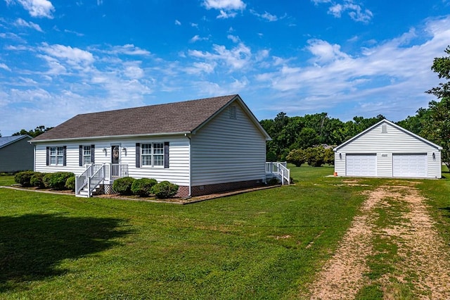 view of front of property featuring a garage, an outbuilding, and a front lawn