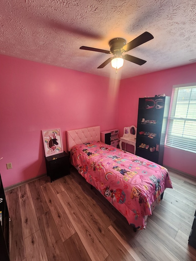 bedroom with visible vents, a textured ceiling, wood finished floors, and a ceiling fan