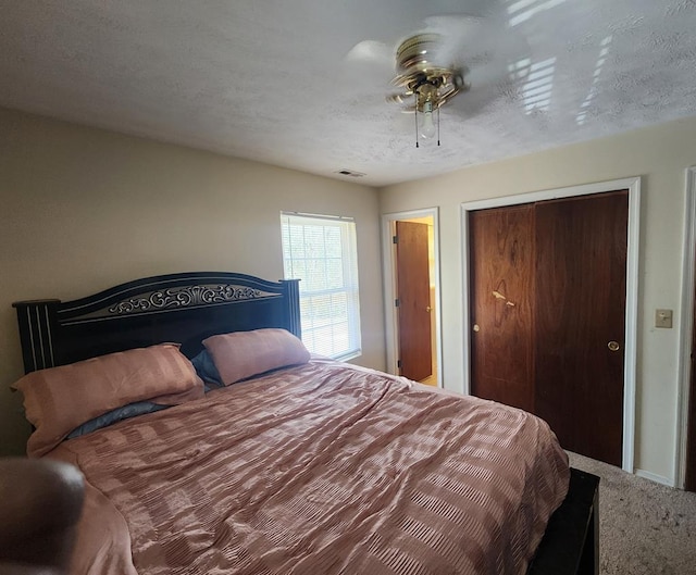 carpeted bedroom with visible vents, a closet, and a textured ceiling