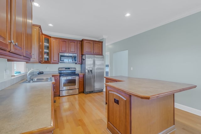 kitchen featuring appliances with stainless steel finishes, a kitchen island, ornamental molding, and sink