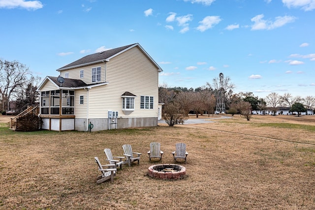 rear view of house with a yard, a fire pit, and a sunroom