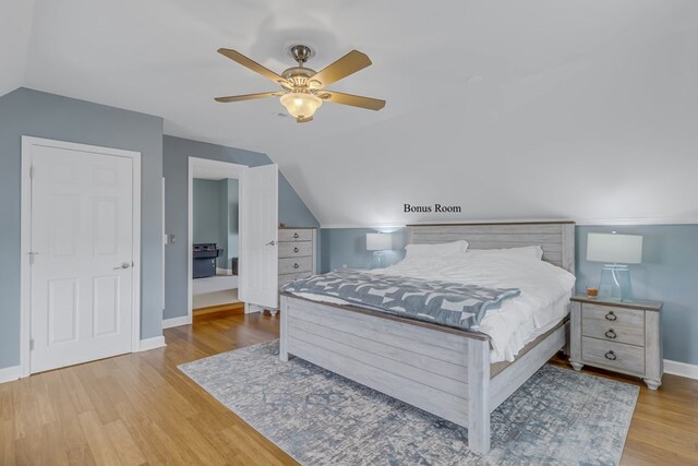 bedroom featuring light hardwood / wood-style floors, vaulted ceiling, and ceiling fan